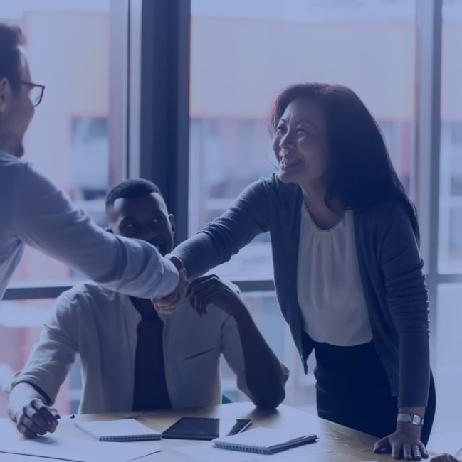 Asian American woman shakes hands with a man, closing a business deal or partnership.